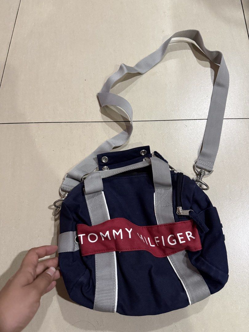 Tommy Hilfiger Navy Blue Mini Duffel Bag (Category: Cross-body Bags) located in Manila. Submitted by metrosen (Listing ID 1464582703, Image 1). Description: - Navy blue mini duffel bag by Tommy Hilfiger - Iconic red and white logo stripe on the front - Main zippered compartment - Interior pocket for organization - Detachable and adjustable shoulder strap - Two small top handles for easy carrying - Ideal for quick getaways or gym essentials.