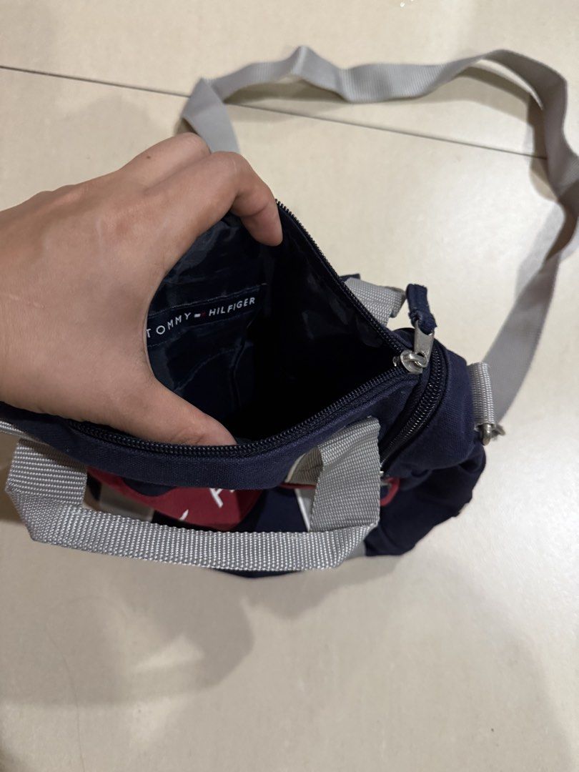 Tommy Hilfiger Navy Blue Mini Duffel Bag (Category: Cross-body Bags) located in Manila. Submitted by metrosen (Listing ID 1464582703, Image 2). Description: - Navy blue mini duffel bag by Tommy Hilfiger - Iconic red and white logo stripe on the front - Main zippered compartment - Interior pocket for organization - Detachable and adjustable shoulder strap - Two small top handles for easy carrying - Ideal for quick getaways or gym essentials.