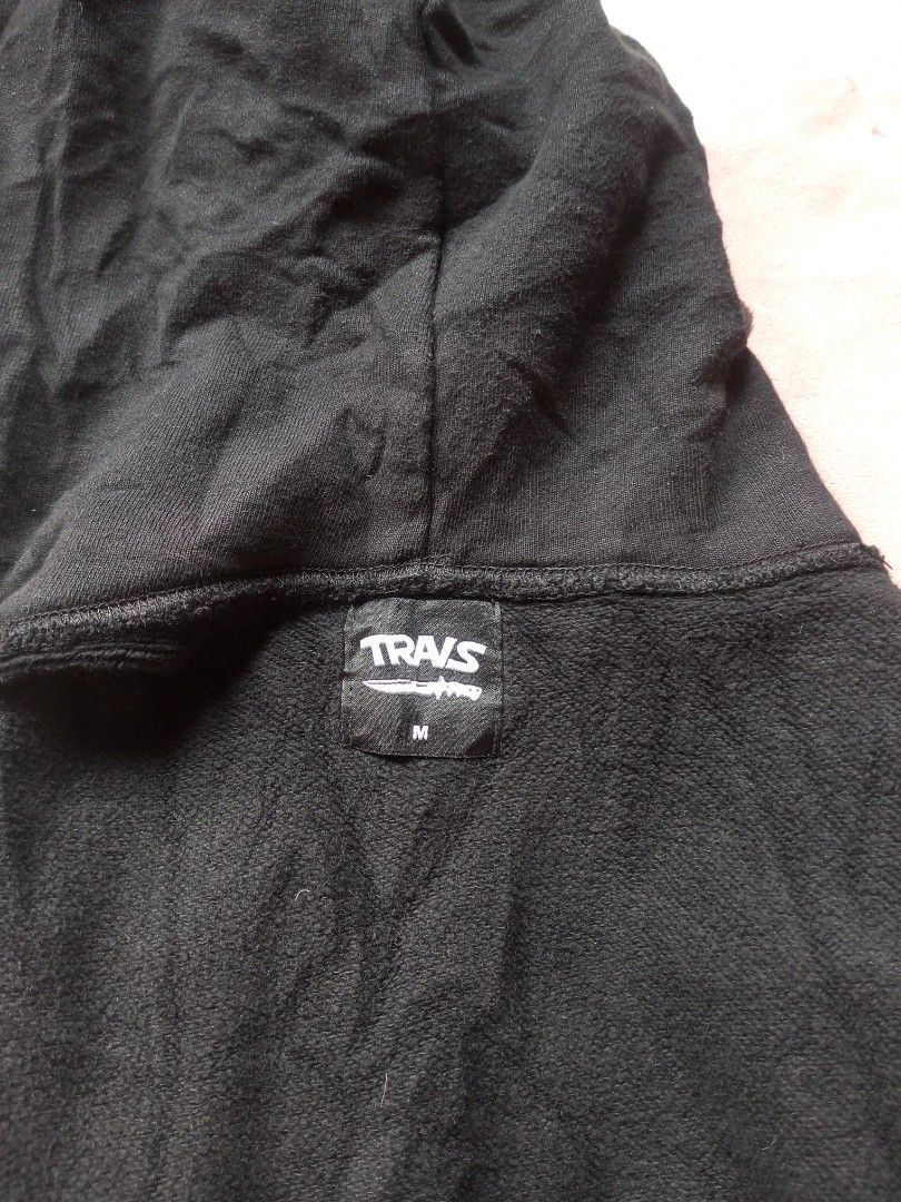TRAVs Black Graphic Hoodie Size M (Category: Hoodies) located in Victorias. Submitted by tobylacua26871 (Listing ID 1464698276, Image 2). Description: - Brand/Model: TRAVs Black Hoodie (japanese brand street wear) - Size: Medium (tag inside collar) - Design: Bold yellow and orange melting text graphic on front - Comfort: Soft interior fleece lining with standard drawstring hood and kangaroo pocket - Condition: Slight wear visible around the pocke