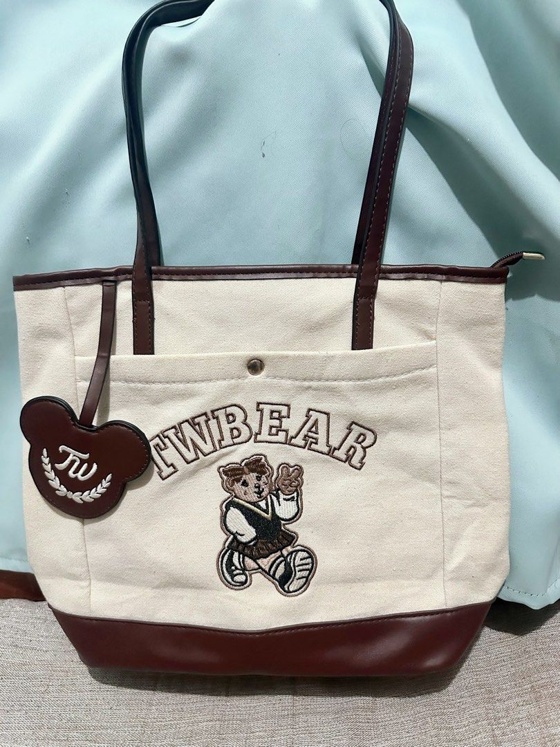 TW Bear Canvas Tote Bag with Leather Trim (Category: Tote Bags) located in Manila. Submitted by shayne2 (Listing ID 1464573600, Image 3). Description: With small inner lining issue need kng tahiin if u want. As seen on last pic not a big deal - Adorable canvas tote bag featuring a cute bear graphic. - 'TWBEAR' embroidery adds a unique touch. - Stylish faux leather trim and handles. - Convenient inner pocket with magnetic snap closure. - Handy ext