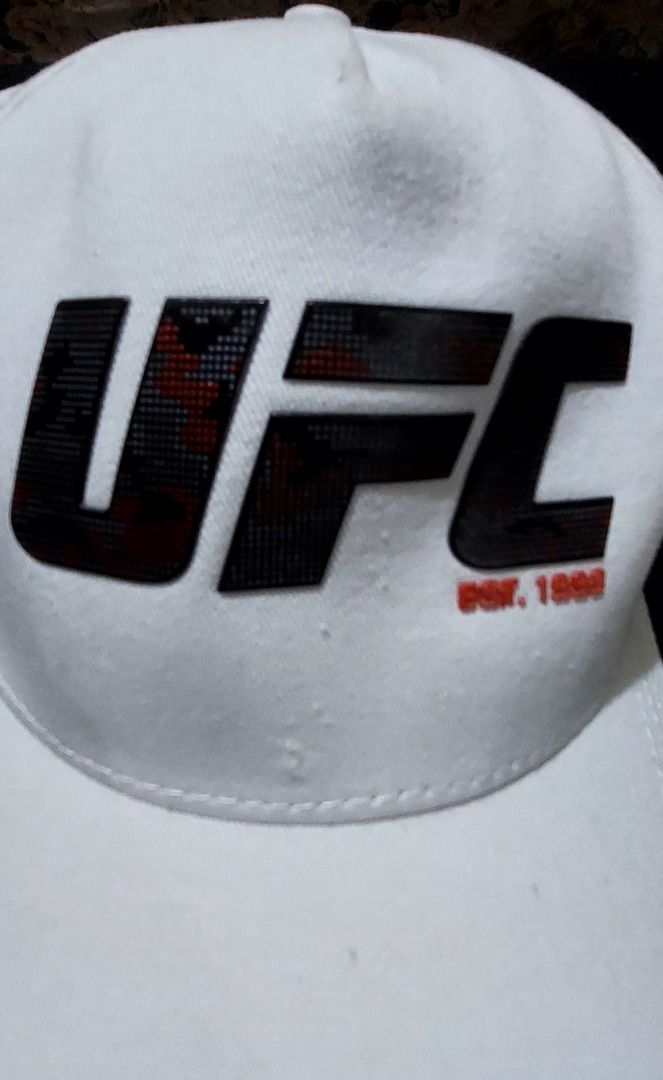 UFC White Cap Adjustable Snapback (Category: Caps & Hats) located in Legazpi City. Submitted by street_uniform (Listing ID 1464740375, Image 2). Description: - 100% authentic UFC merchandise in clean white cotton twill - Features a bold digital camouflage logo with striking red branding details - Adjustable plastic snapback closure for a comfortable, custom fit - Premium interior finish with branded red UFC seam tape - Condition: Brand new / Exce