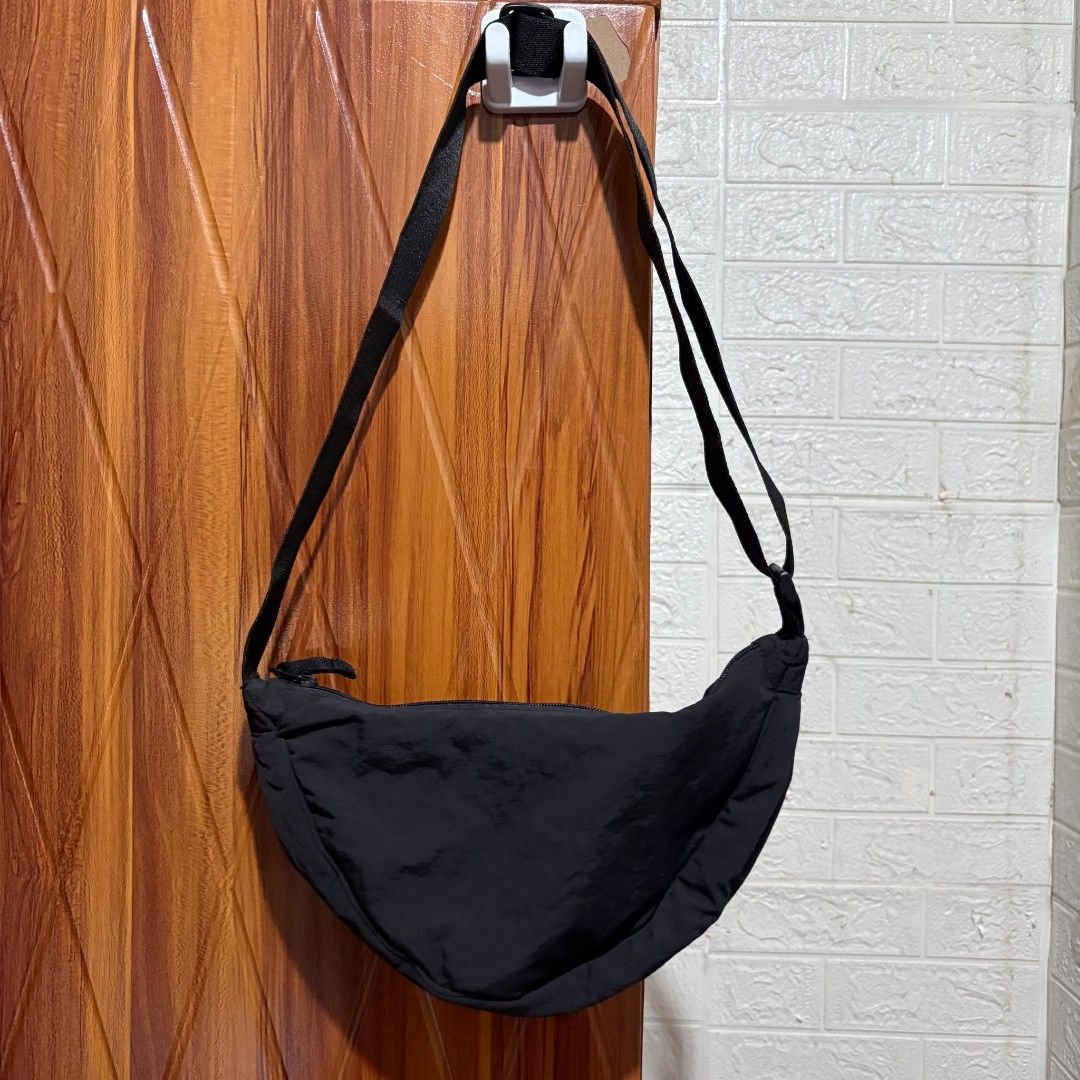 Uniqlo Round Mini Shoulder Bag Black (Category: Shoulder Bags) located in Carmen. Submitted by ar_thrift00 (Listing ID 1464715887, Image 2). Description: - Brand: Uniqlo - Color: Classic Black - Material: Soft nylon shell with polyester filling and lining - Closure: Smooth zipper with dual pull tabs - Storage: Includes an inside zip pocket for small items - Strap: Adjustable strap with sturdy buckle - Style: Practical everyday crossbody bag with 