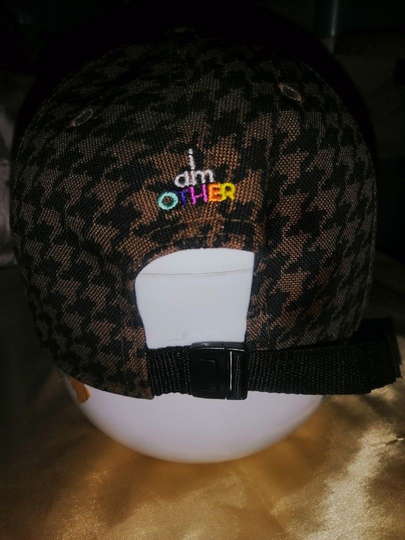 Uniqlo x i am OTHER Houndstooth Cap (Category: Caps & Hats) located in Quezon City. Submitted by rolenalma (Listing ID 1464707600, Image 2). Description: - Brand: Uniqlo x Pharrell Williams (i am OTHER collaboration) - Design: Brown and black houndstooth pattern on crown and brim - Details: Multicolored embroidered lettering on the back - Fit: Adjustable nylon strap with plastic buckle closure - Condition: Excellent, clean black interior lining w