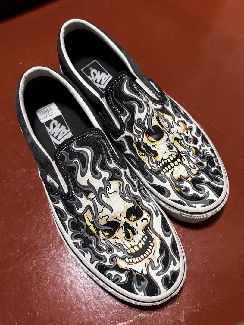 Vans Classic Slip-On Skull Flame Print (Category: Sneakers) located in Manila. Submitted by finderskeepersmnl_092026 (Listing ID 1464710278, Image 1). Description: - Brand: Vans - Style: Classic Slip-On with elastic side goars - Design: Bold skull and flame graphic in black, white, orange, and green - Soles: Signature waffle rubber outsoles - Perfect for daily wear and making a street-style statement.