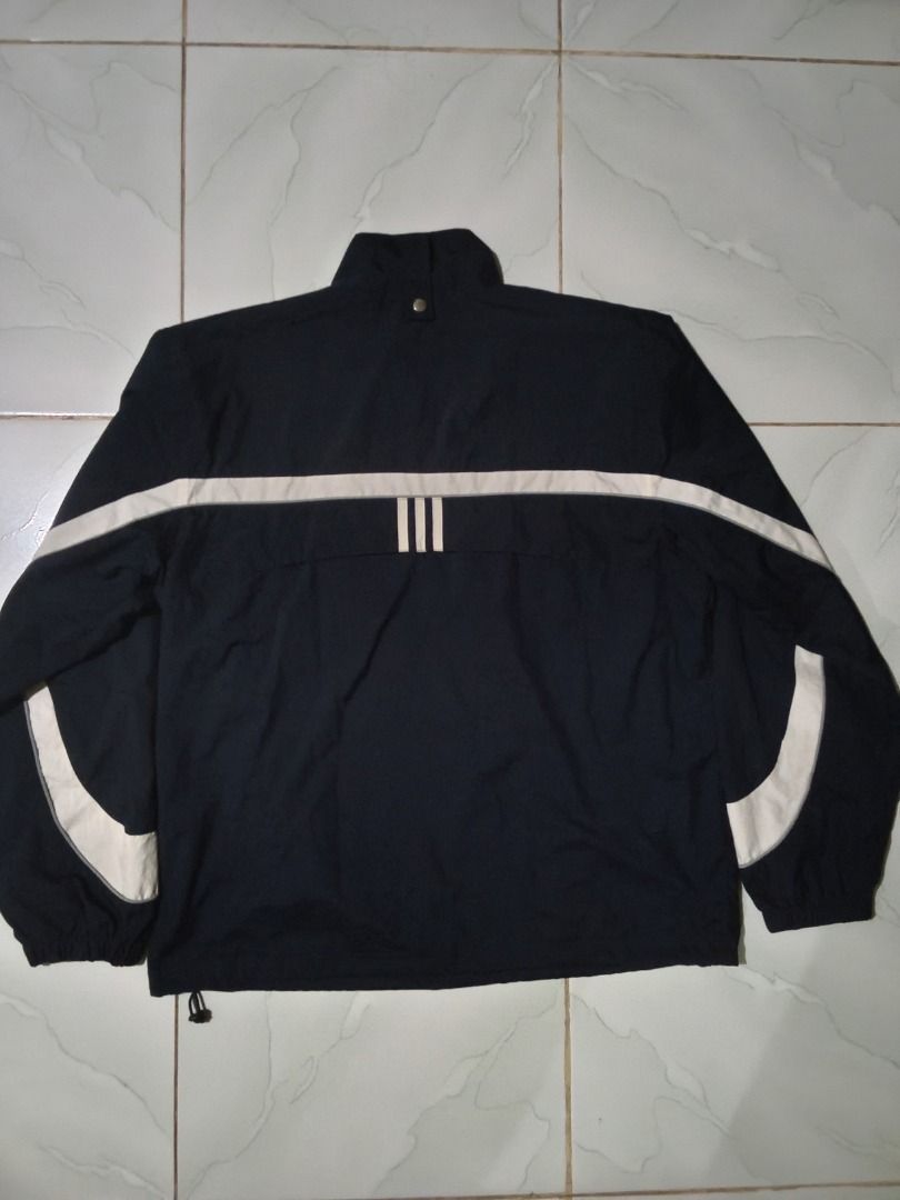Vintage Adidas Navy Blue Windbreaker Jacket (Category: Coats, Jackets and Outerwear) located in Caloocan City. Submitted by mysticdog-6a6b (Listing ID 1464737411, Image 2). Description: - Brand: Adidas - Color: Navy blue with white accent stripes - Features: Embroidered logo, stand-up collar with snap button, and mesh interior lining - Fit: Adjustable bungee cord hem for a customizable fit - Style: Classic sporty look, ideal layering piece for br