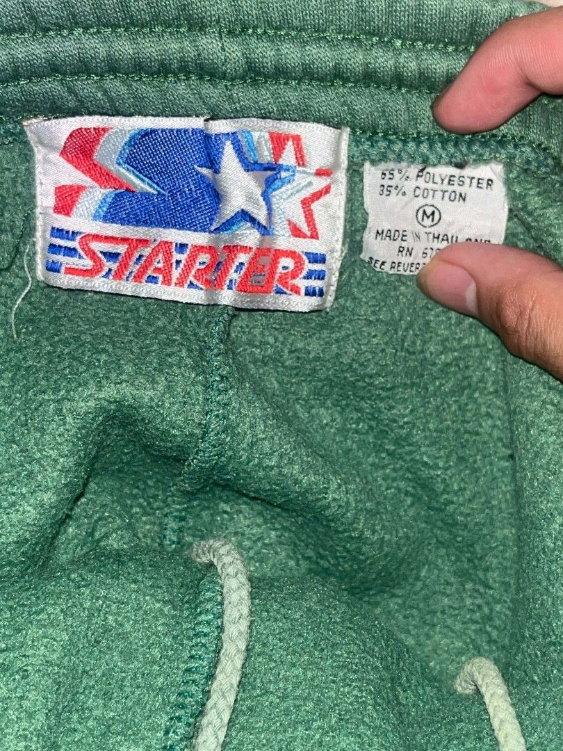 Vintage Starter Athletic Shorts "CELTICS" (Category: Shorts) located in Aguinaldo. Submitted by true.north_archive (Listing ID 1464677691, Image 3). Description: - Brand: Starter - Color: Green - Size: Medium - Features: 'CELTICS' on left leg, elastic waistband with drawstring, back right pocket - Material: 65% Polyester, 35% Cotton.