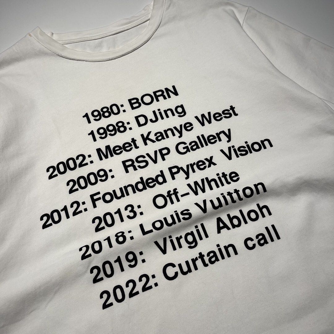 Virgil Abloh "Curtain Call" Legacy Timeline Tee (Category: Tshirts & Polo Shirts ) located in Balanga. Submitted by goodiegarments (Listing ID 1464584056, Image 2). Description: Virgil Abloh "Curtain Call" Legacy Timeline Tee A minimalist yet profound tribute to a modern fashion visionary. This white streetwear tee chronicles the monumental timeline of Virgil Abloh—from his early days DJing and founding Pyrex Vision, to taking the helm at Off-Whi