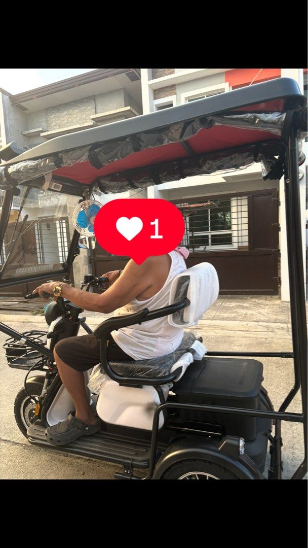 Wanyuan Electric Tricycle With Canopy And Storage (Category: Motorbikes for Sale) located in Manila. Submitted by jobithings (Listing ID 1464737921, Image 2). Description: Wanyuan electric tricycle with a full black roof canopy and front windshield. Includes handlebars, front storage basket, cushioned seating with backrest, and overhead fan. Rear storage box fitted behind the seat. Black and white frame design with LED light bar on top roof edge.