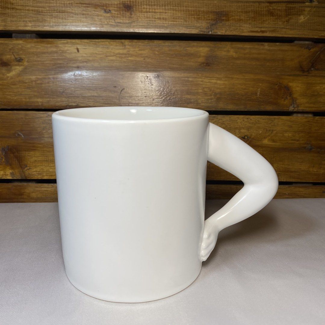 White Ceramic Mug with Arm Handle (Category: Coffee & Tea Tableware) located in Quezon City. Submitted by oliviararo46032 (Listing ID 1464673715, Image 1). Description: - Unique white ceramic mug - Features a quirky arm-shaped handle - Ideal for coffee, tea, or any beverage - Adds a fun touch to your kitchen or desk - Great gift for someone with a sense of humor - Generous liquid capacity.