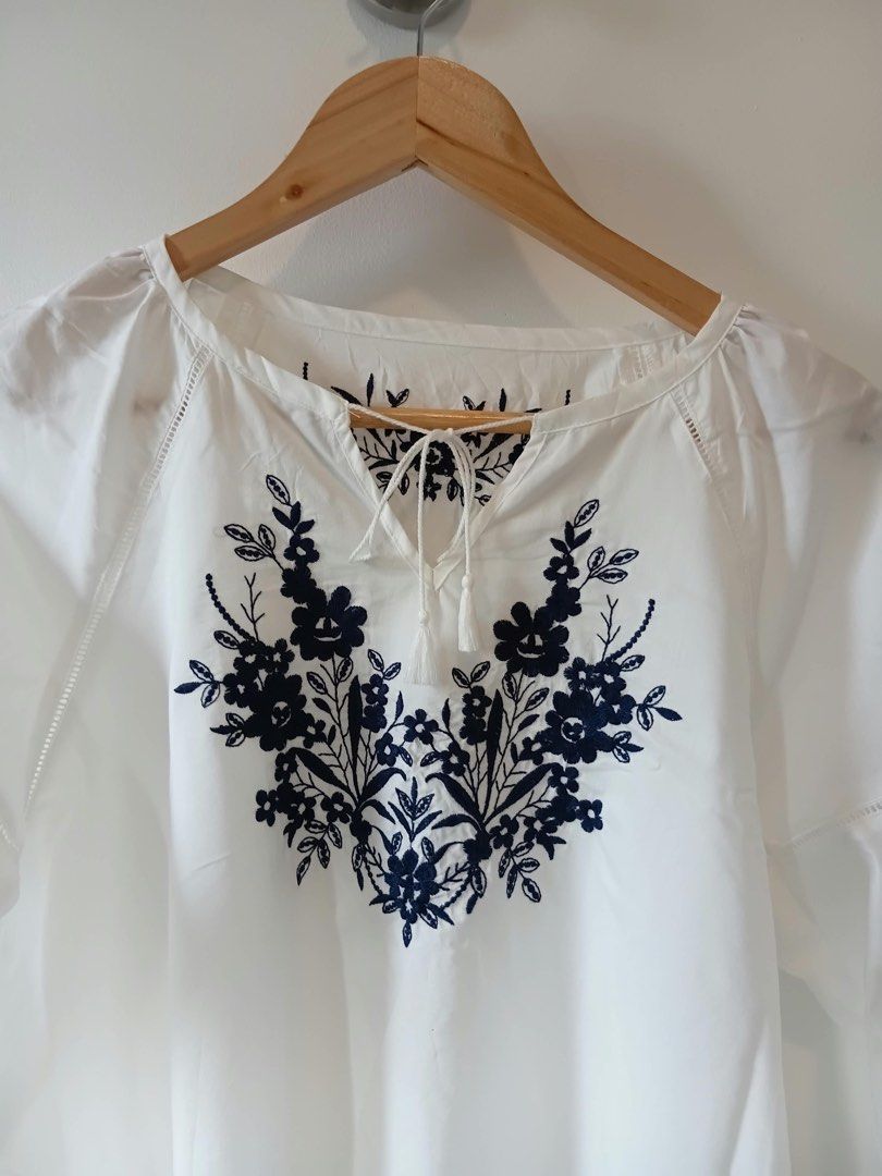 White Embroidered Blouse with Tassel Tie (Category: Blouses) located in Manila. Submitted by wisecat.4a7eea (Listing ID 1464635314, Image 3). Description: - Elegant white long-sleeved blouse - Beautiful navy blue floral embroidery on the front - Unique tassel tie detail at the neckline - Ruffled hem on the sleeves - Fits size Medium to Large (M-L) - Ideal for casual wear and everyday style.