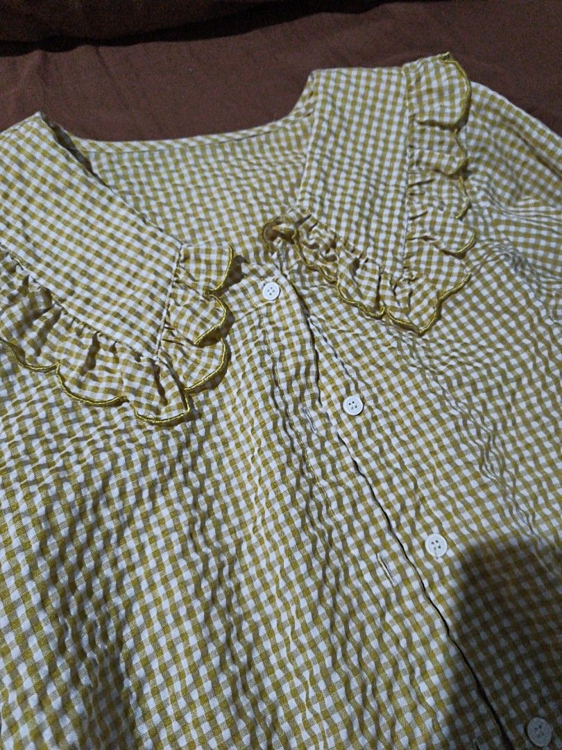 yellow long sleeve blouse (Category: Blouses) located in Manila. Submitted by xoesnup1 (Listing ID 1464741079, Image 3). Description: - Pattern: Yellow and white check seersucker - Details: Big statement collar with ruffled edges and gold piping trim - Closure: Button-down front with white buttons - Sleeves: Long sleeves with gathered elastic cuffs and button closure - Style: Casual, great for layering, skirts, or jeans - Condition: Clean and rea