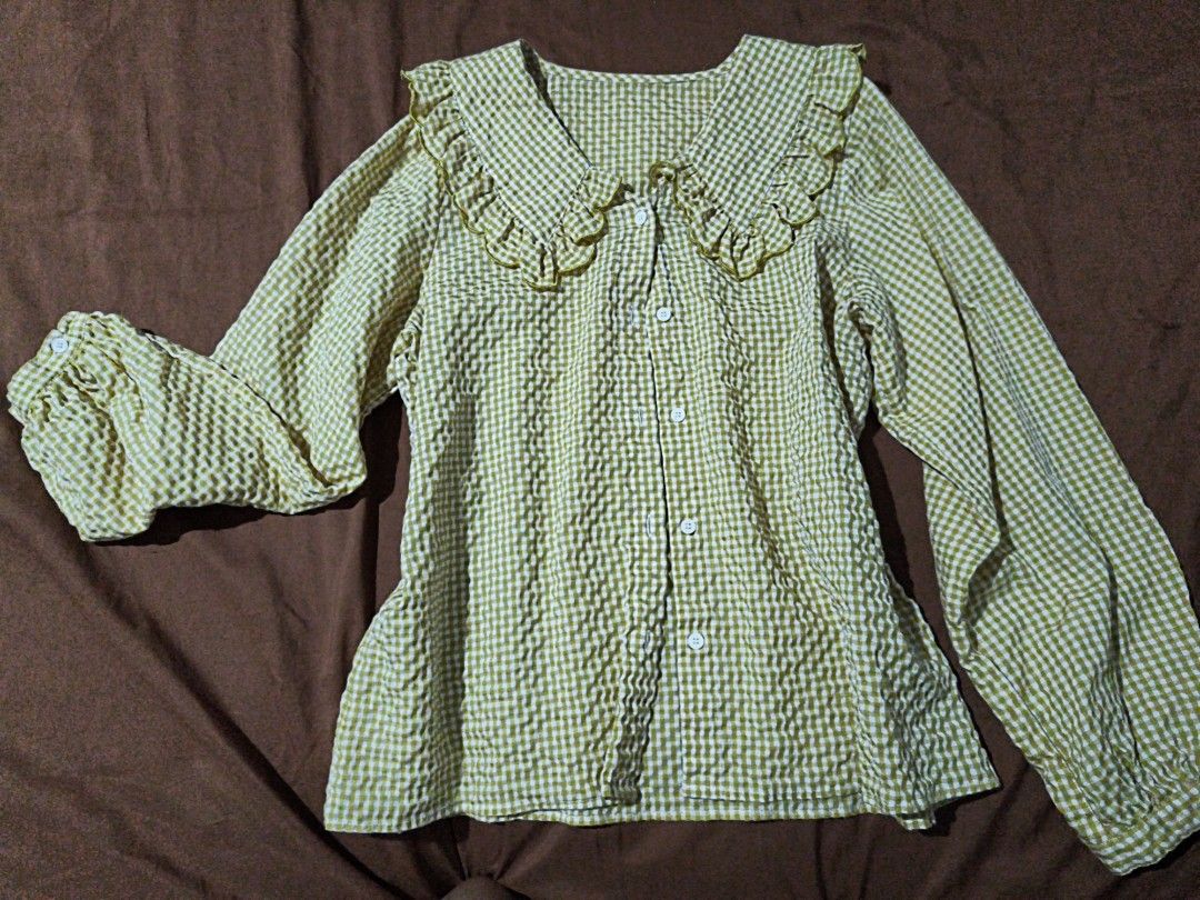 yellow long sleeve blouse (Category: Blouses) located in Manila. Submitted by xoesnup1 (Listing ID 1464741079, Image 2). Description: - Pattern: Yellow and white check seersucker - Details: Big statement collar with ruffled edges and gold piping trim - Closure: Button-down front with white buttons - Sleeves: Long sleeves with gathered elastic cuffs and button closure - Style: Casual, great for layering, skirts, or jeans - Condition: Clean and rea