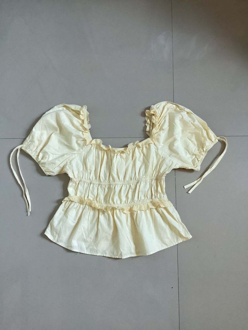 Yellow Puff Sleeve Square Neck Smocked Top (Category: Blouses) located in Siniloan. Submitted by mari_881709 (Listing ID 1464618395, Image 1). Description: - Adorable yellow top with charming puff sleeves. - Features a flattering square neckline. - Smocked detailing on the bodice for a comfortable fit. - Delicate ruffled trim along the hem. - Adjustable ties on the sleeves for a customizable look. - Perfect for both casual outings and dressier ev