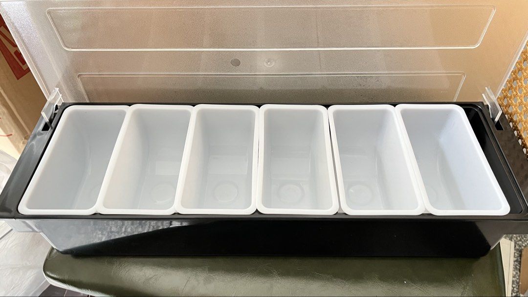 6-Compartment Bar Condiment Holder with Lid (Category: Food Organization & Storage) located in Manila. Submitted by caprence0228 (Listing ID 1464787781, Image 3). Description: - Black plastic base with 6 removable white containers - Clear hinged lid to keep items clean and covered - Ideal for toppings, garnishes, or meal prep ingredients - Includes original white cardboard box.