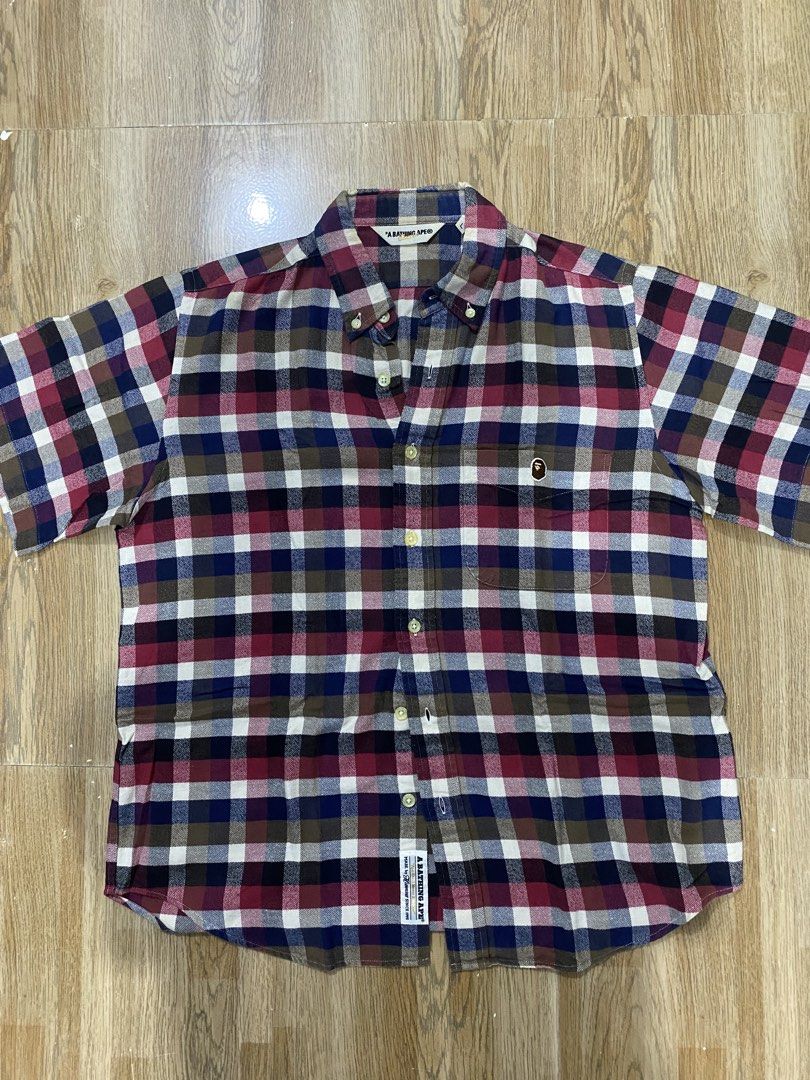 A Bathing Ape (BAPE) (Category: Formal Shirts) located in Cebu City. Submitted by trppydre (Listing ID 1464881199, Image 1). Description: This is a short-sleeve button-down plaid shirt from A Bathing Ape (BAPE) featuring a multi-color check pattern in red, blue, white, and brown with a small ape head logo on the chest pocket..