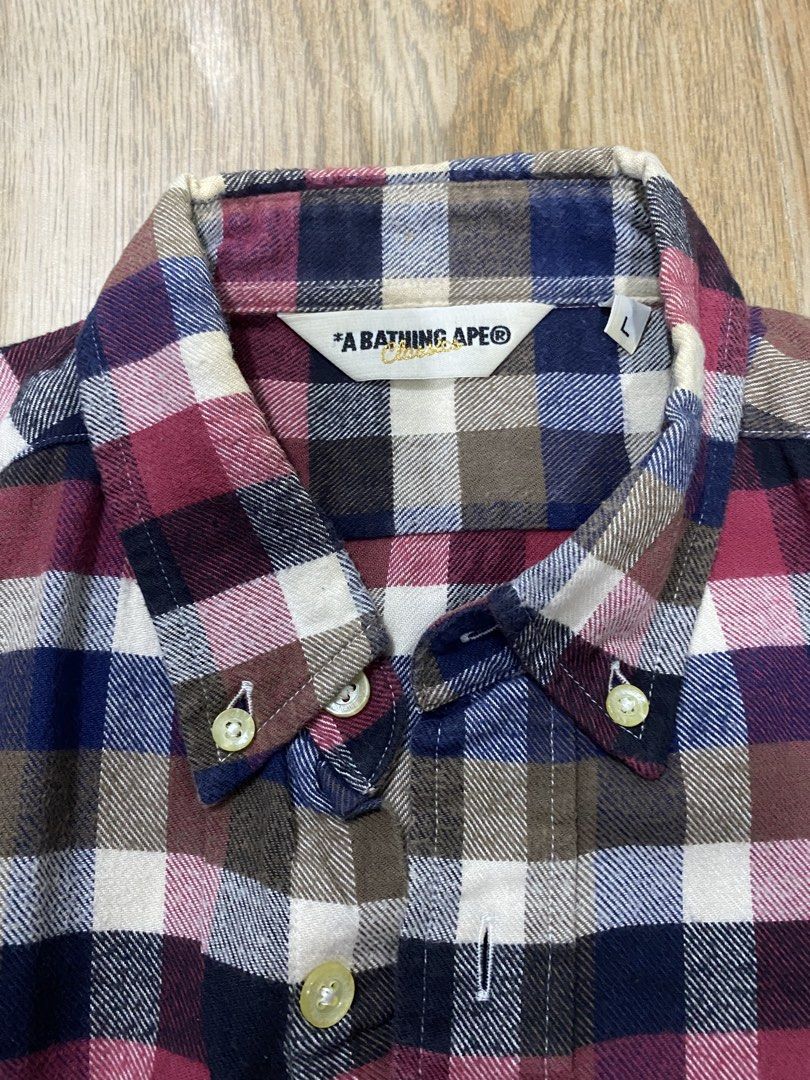A Bathing Ape (BAPE) (Category: Formal Shirts) located in Cebu City. Submitted by trppydre (Listing ID 1464881199, Image 2). Description: This is a short-sleeve button-down plaid shirt from A Bathing Ape (BAPE) featuring a multi-color check pattern in red, blue, white, and brown with a small ape head logo on the chest pocket..