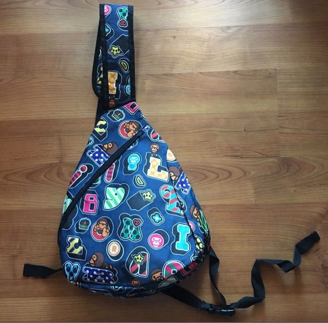 A Bathing Ape BAPE ABC Camo Sling Bag (Category: Sling Bags) located in Rizal. Submitted by timelessfinds89_ (Listing ID 1464918754, Image 1). Description: - Brand: BAPE - Design: Blue multi-color ape head graphic pattern - Material: Durable canvas - Strap: Adjustable black strap with plastic buckle closure - Storage: Diagonal front zipper pocket and compact main compartment for daily essentials - Condition: Clean interior and exterior, no heavy 