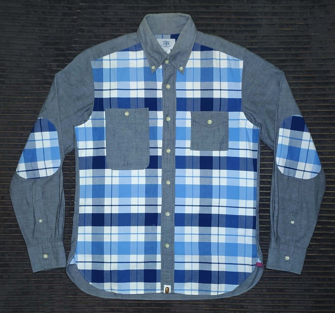 A Bathing Ape BAPE Blue Plaid Patchwork Button-Up Shirt (Category: Tshirts & Polo Shirts ) located in Manila. Submitted by norathrifted (Listing ID 1464802043, Image 2). Description: - Brand: A Bathing Ape (BAPE) - Item: Blue plaid patchwork button-up shirt - Size: Medium (M) - Details: Blue/white check pattern with grey chambray sleeves, collar, and dual chest pockets - Unique Features: Plaid elbow patches, button-down collar, and signature BAPE