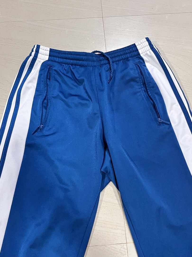 Adidas Adibreak Track Pants (Category: Joggers) located in Paranaque City. Submitted by jiyodanpoole (Listing ID 1464816232, Image 2). Description: Brand: Adidas - Color: Blue with white side stripes - Features: Full snap buttons down both legs - Waistband: Elastic with adjustable drawstring - Pockets: Secure zippered side pockets - Details: Branded logo patches near the lower leg - Good condition RFS: Declutter Slightly negotiable‼️ Pick-up, mee