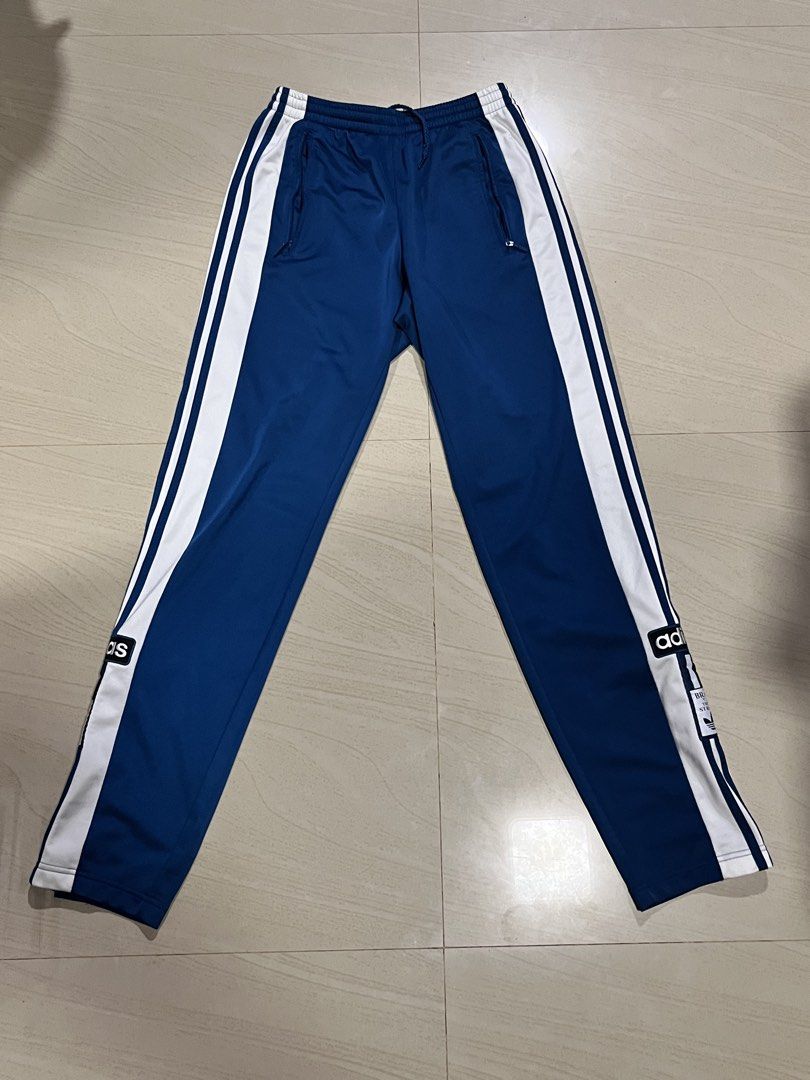 Adidas Adibreak Track Pants (Category: Joggers) located in Paranaque City. Submitted by jiyodanpoole (Listing ID 1464816232, Image 1). Description: Brand: Adidas - Color: Blue with white side stripes - Features: Full snap buttons down both legs - Waistband: Elastic with adjustable drawstring - Pockets: Secure zippered side pockets - Details: Branded logo patches near the lower leg - Good condition RFS: Declutter Slightly negotiable‼️ Pick-up, mee