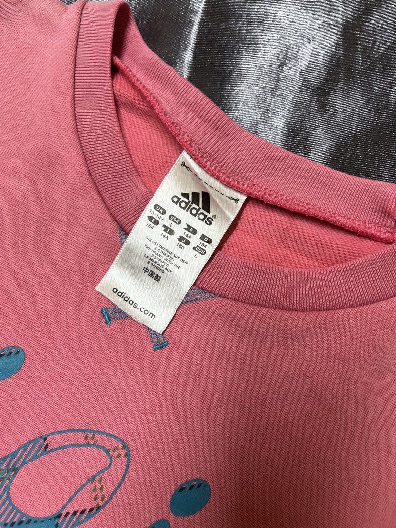 Adidas Adigirl Pink Sweatshirt (Category: Coats, Jackets and Outerwear) located in Cavite. Submitted by bellewii (Listing ID 1464910325, Image 2). Description: - Brand: Adidas - Style: Adigirl Crewneck Sweatshirt - Color: Pink with plaid graphic - Size: Tagged 13-14Y (UK/USA L, 164) - Features: Soft fleece inner lining, iconic blue trefoil logo - Flaws: Noticeable scratch near center front chest and a fade mark near the bottom hem - Perfect for c