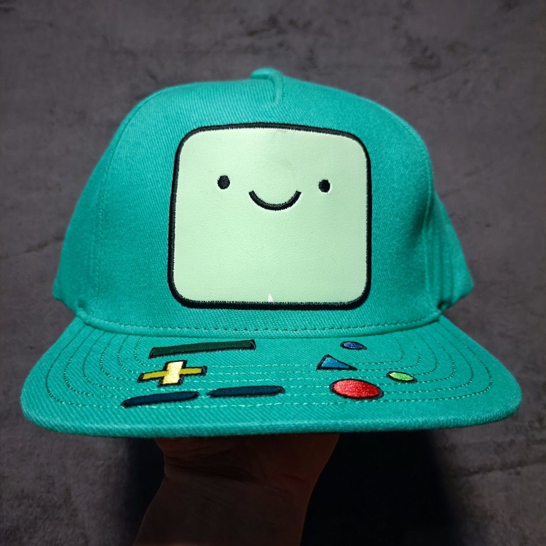 Adventure Time BMO Snapback Cap (Category: Caps & Hats) located in Manila. Submitted by nye.seller (Listing ID 1464886425, Image 1). Description: - Official Cartoon Network Adventure Time merchandise - Green snapback cap featuring BMO graphic on the front - Brim detailed with embroidered game controller buttons - Under-brim features the Adventure Time logo on a black panel - Adjustable plastic strap at the back for a custom fit - Brand new with t