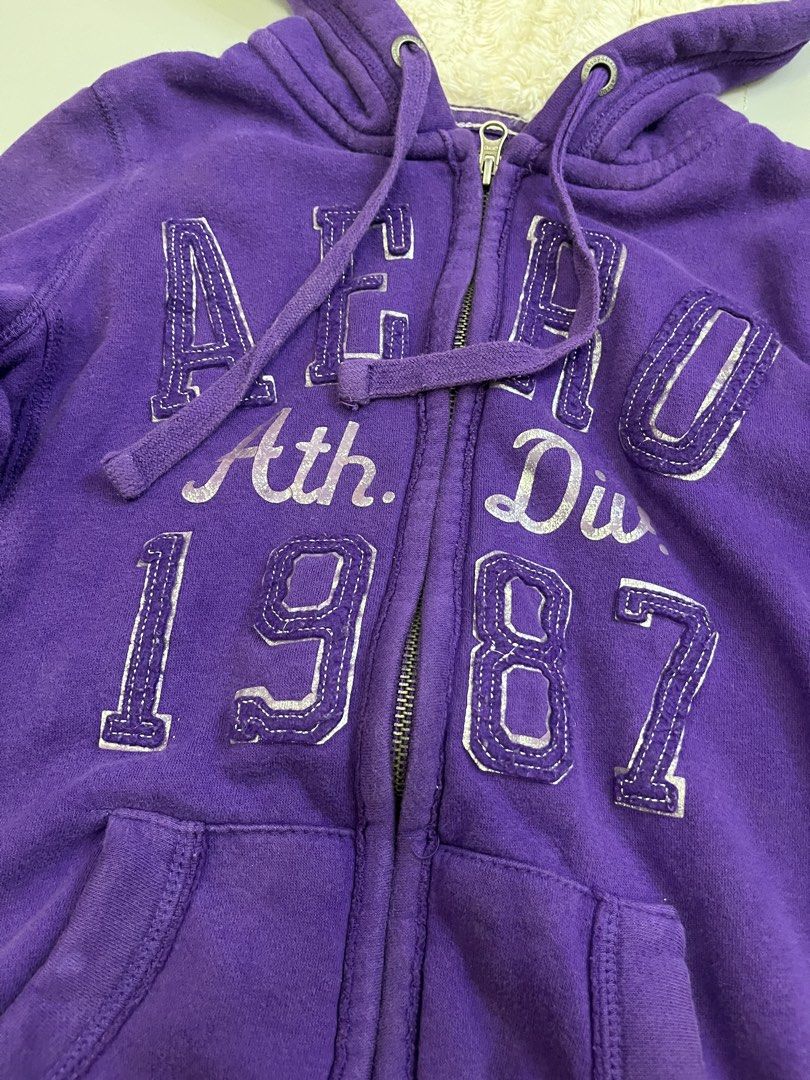 Aeropostale Fur Jacket (Category: Coats, Jackets and Outerwear) located in Mabalacat. Submitted by aas_thriftfings (Listing ID 1464783432, Image 2). Description: - Brand: Aeropostale - Color: Purple with silver distressed chest lettering ('Aero Ath. Div. 1987') - Lining: Cozy white fuzzy sherpa inside the hood - Features: Full zip-up, front pockets, and matching drawstring cords - Details: Ribbed cuffs and hem for extra comfort and fit - Conditio