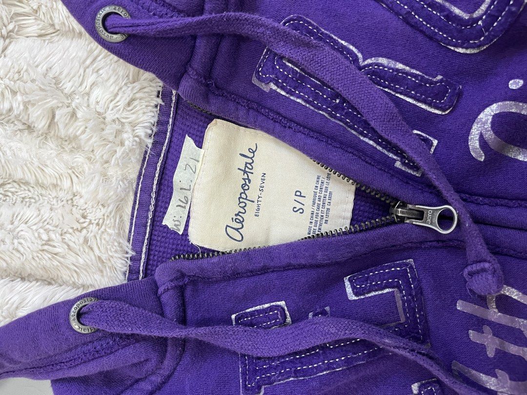 Aeropostale Fur Jacket (Category: Coats, Jackets and Outerwear) located in Mabalacat. Submitted by aas_thriftfings (Listing ID 1464783432, Image 3). Description: - Brand: Aeropostale - Color: Purple with silver distressed chest lettering ('Aero Ath. Div. 1987') - Lining: Cozy white fuzzy sherpa inside the hood - Features: Full zip-up, front pockets, and matching drawstring cords - Details: Ribbed cuffs and hem for extra comfort and fit - Conditio