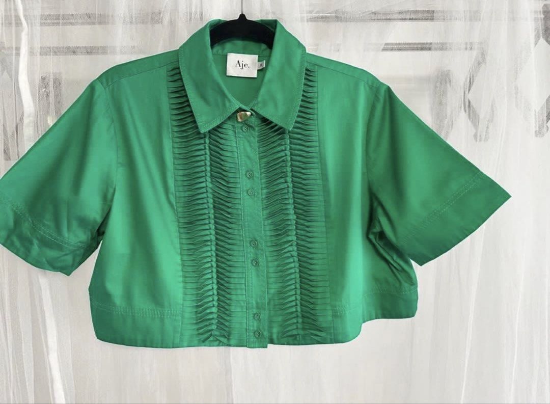 Aje Emerald Tidal Tucked Crop Top (Category: Shirts) located in Iloilo. Submitted by ele.girl (Listing ID 1464902086, Image 2). Description: - Brand: Aje - Color: Bright green - Style: Short sleeve crop top - Details: Unique pleated detailing along the front button placket - Fit: Structured fabric that holds its shape, hits right at the waistline - Condition: Great statement piece for warm weather.