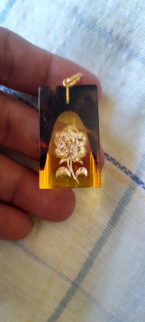 Amber pendant with yellow flower embedded (Category: Necklaces) located in Bocaue. Submitted by marajapansurplus (Listing ID 1464784281, Image 3). Description: - Amber-style clear resin pendant with an embedded yellow flower design - Stylish dark tortoiseshell pattern accent on one end - Fitted with a gold metal loop at the top for easy hanging on chains or cords - Smooth, high-gloss polished finish all around - Clean and ready to be made into a 