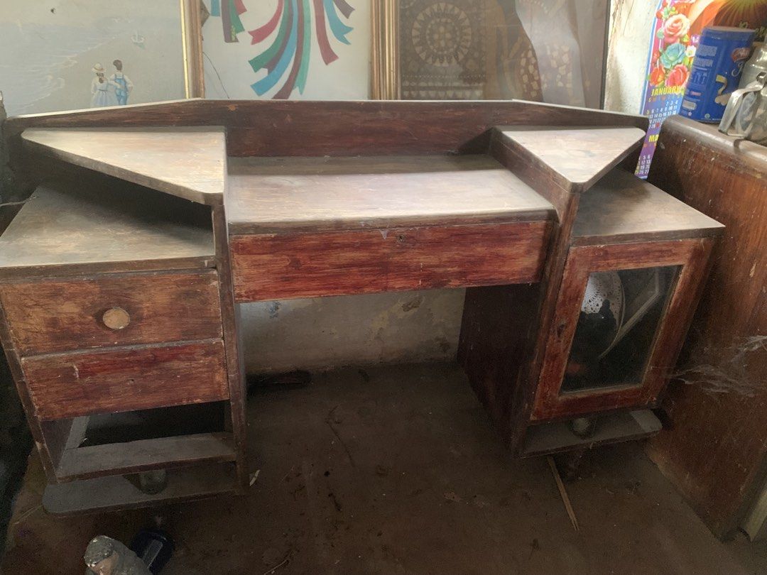 Antique narra dresser (Category: Tables & Sets) located in Quezon City. Submitted by sojisup (Listing ID 1464879923, Image 2). Description: - Vintage wooden vanity table with a charming reddish-brown finish - Features a large central desktop, raised backboard, and corner ledges - Multi-level shelving and multiple drawers on the left - Glass-paneled cabinet door on the right - Sturdy and solid build, perfect for a restoration project - Needs a goo