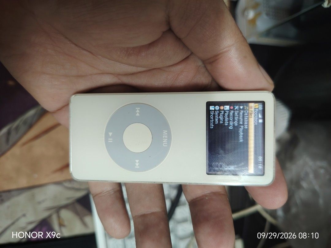 Apple iPod nano 2GB White (Category: Portable Music Players) located in Manila. Submitted by flashghie (Listing ID 1464965031, Image 1). Description: - Model: Apple iPod nano (White) - Storage: 2GB capacity - Features: Classic click wheel design & custom Rockbox firmware - Condition: Screen turns on, fully functional, with visible scratches on the chrome back from regular use - Included: Portable music player ready for your tunes.