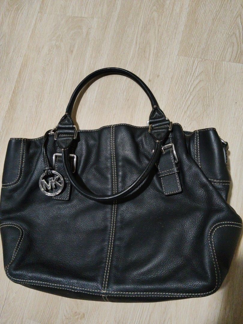 AUTHENTIC Michael Kors Black Leather Handbag (Category: Luxury Bags & Wallets) located in Quezon City. Submitted by letsgroove (Listing ID 1464880478, Image 1). Description: - 100% Authentic Michael Kors tote bag - Genuine black pebble leather with contrast stitching - Silver-tone hardware featuring a front buckle accent and hanging MK charm - Spacious main compartment with signature monogram lining and leather brand patch - Comfortable double sh