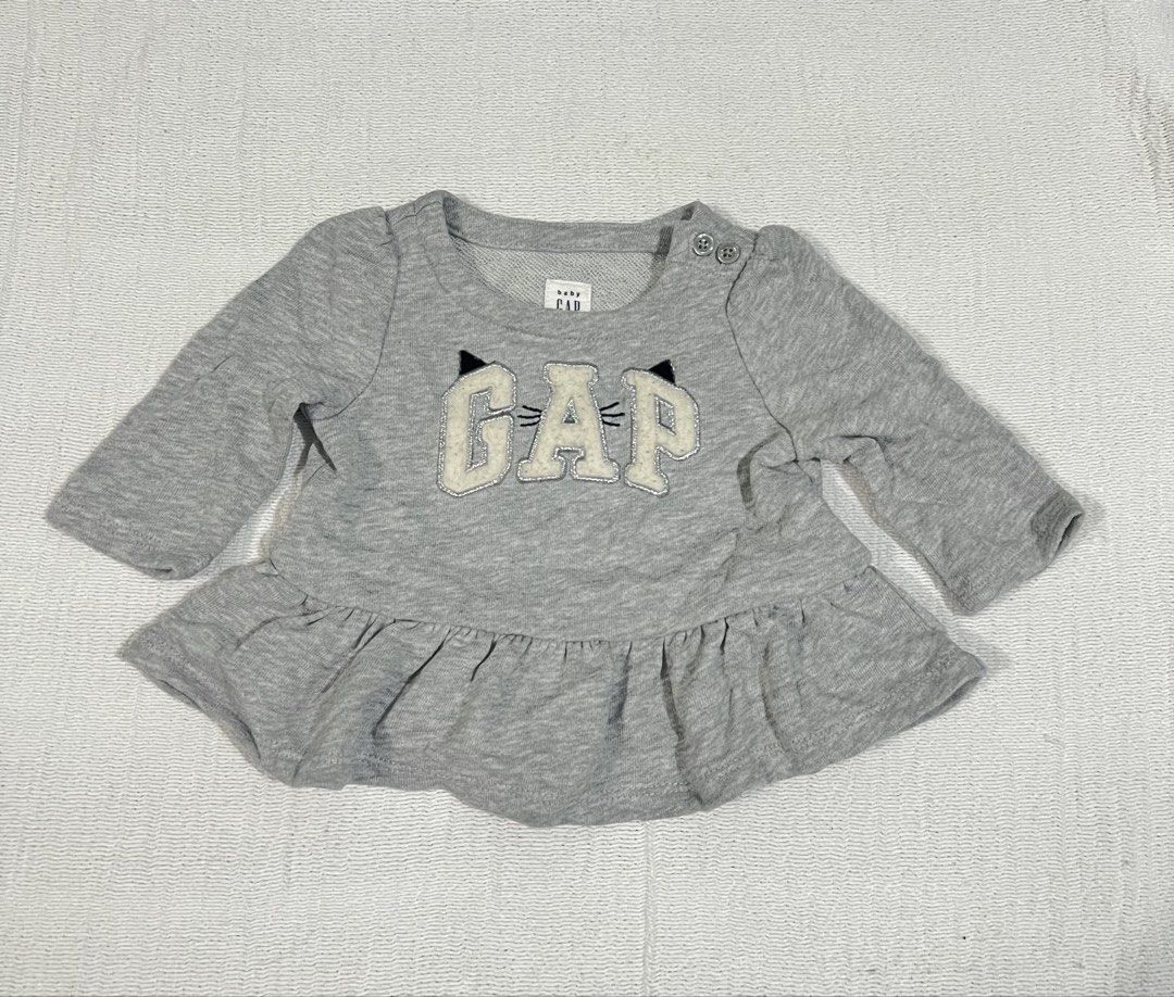 Baby Gap Grey Cat Peplum Top (Category: Sleeveless) located in Quezon City. Submitted by charlenedv58782 (Listing ID 1464779871, Image 1). Description: - Brand: Baby Gap 0-3 - Color: Grey - Design: Cute cat face graphic lettering on the front - Details: Ruffled peplum hem - Convenience: Shoulder buttons for easy dressing - Material: Soft cotton blend - Condition: Great addition to any little girl's wardrobe.
