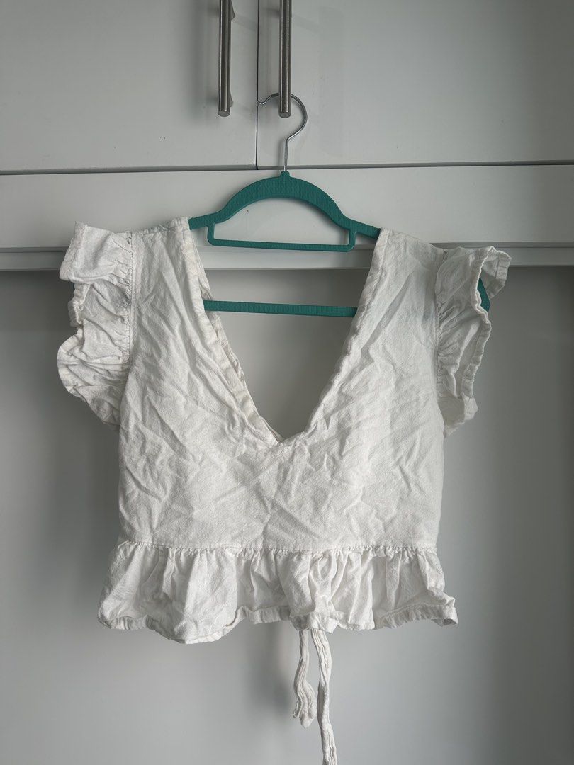 Backless White Ruffle Crop Peplum Top (Category: Sleeveless) located in Quezon City. Submitted by erika.h (Listing ID 1464821389, Image 1). Description: - Color: White (linen-look fabric) - Style: Crop top with peplum hem - Neckline: Deep V-neck - Sleeves: Ruffled cap sleeves - Closure: Adjustable back tie - Fit: Lightweight and perfect for warm weather - Pairing: Great with high-waisted shorts or denim jeans.