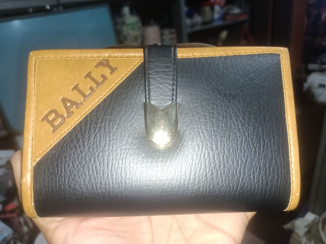 Bally leather wallet black and brown (Category: Wallets & Card Holders) located in Munoz. Submitted by larryc1212 (Listing ID 1464899398, Image 2). Description: - Authentic Bally bi-fold wallet made in Italy - Stylish black and tan leather mix with elegant gold foil logo - Secure snap button closure and vintage-style kiss-lock coin compartment - Multiple card slots and convenient ID window inside - Condition: Shows some edge wear and natural agin