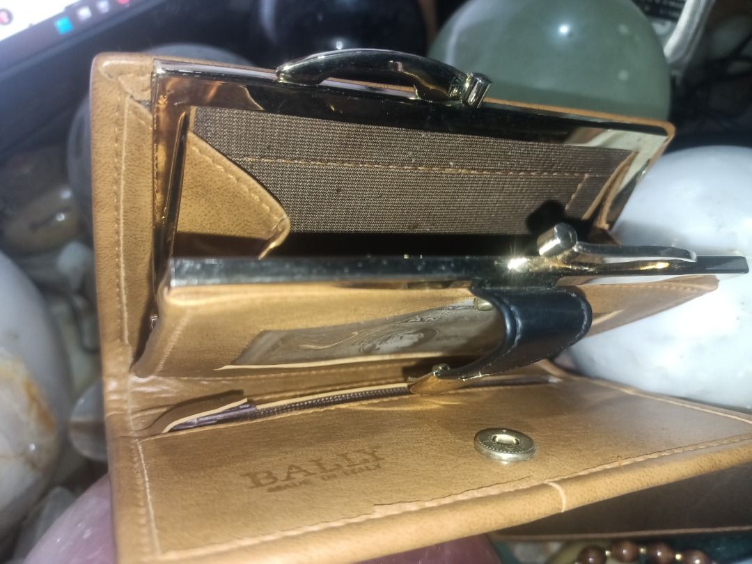 Bally leather wallet black and brown (Category: Wallets & Card Holders) located in Munoz. Submitted by larryc1212 (Listing ID 1464899398, Image 3). Description: - Authentic Bally bi-fold wallet made in Italy - Stylish black and tan leather mix with elegant gold foil logo - Secure snap button closure and vintage-style kiss-lock coin compartment - Multiple card slots and convenient ID window inside - Condition: Shows some edge wear and natural agin