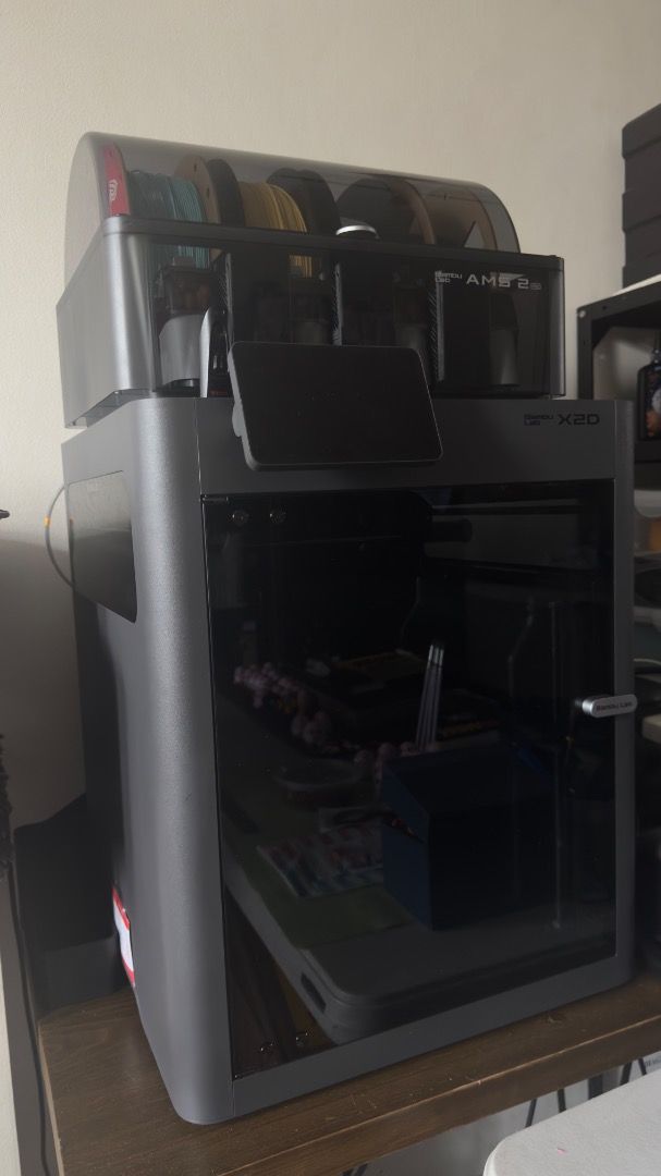 Bambu Lab X2D 3D Printer with AMS 2 Pro (Category: Printers, Scanners & Copiers) located in Manila. Submitted by layerforgeph (Listing ID 1464770583, Image 1). Description: - Model: Bambu Lab X2D 3D Printer - Bundle: Includes AMS 2 Pro multi-material unit and 4 loaded filament spools - Design: Fully enclosed grey body with front touch display panel - Features: High-speed printing setup, perfect for multi-color projects - Inclusions: Everything sh