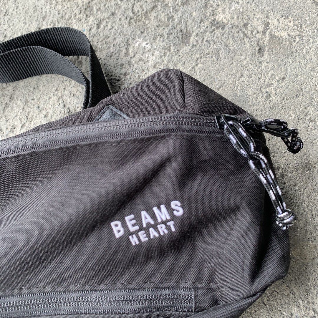 Beams Heart Black Waist Bag (Category: Belt bags, Clutches and Pouches) located in Polangui. Submitted by b0ssl00ts (Listing ID 1464807091, Image 2). Description: - Brand: Beams Heart - Material: Sturdy black canvas with white embroidered branding - Storage: Main compartment with a handy diagonal zip pocket - Hardware: Smooth zippers with stylish black and white speckled cord pulls - Fit: Adjustable black strap with a secure plastic buckle closur