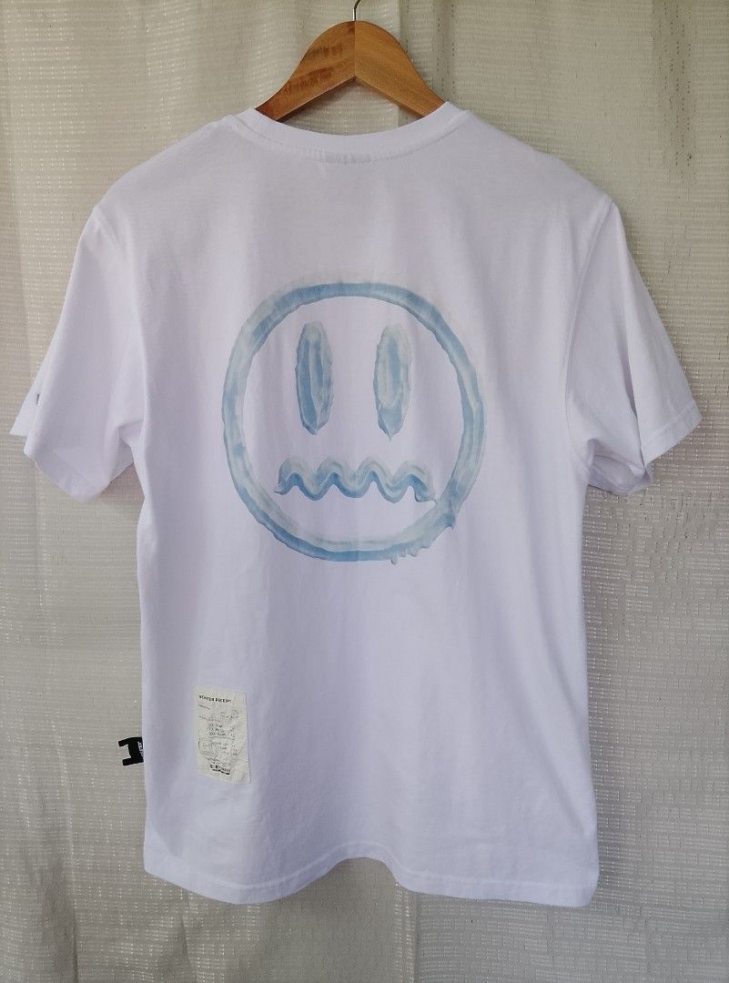 BEASTER White Graphic Tee with Receipt Patch (Category: Tshirts & Polo Shirts ) located in Tayum. Submitted by purephoenix.0f7166 (Listing ID 1464813090, Image 2). Description: - Brand: Beaster - 20.5 x 27 dimes - like new condition - no issue - Color: White with blue accents - Design: Blue brushstroke script logo on front, large blue dripping smiley graphic on back - Details: Faux receipt patch with barcode on back hem, woven sleeve and side tag