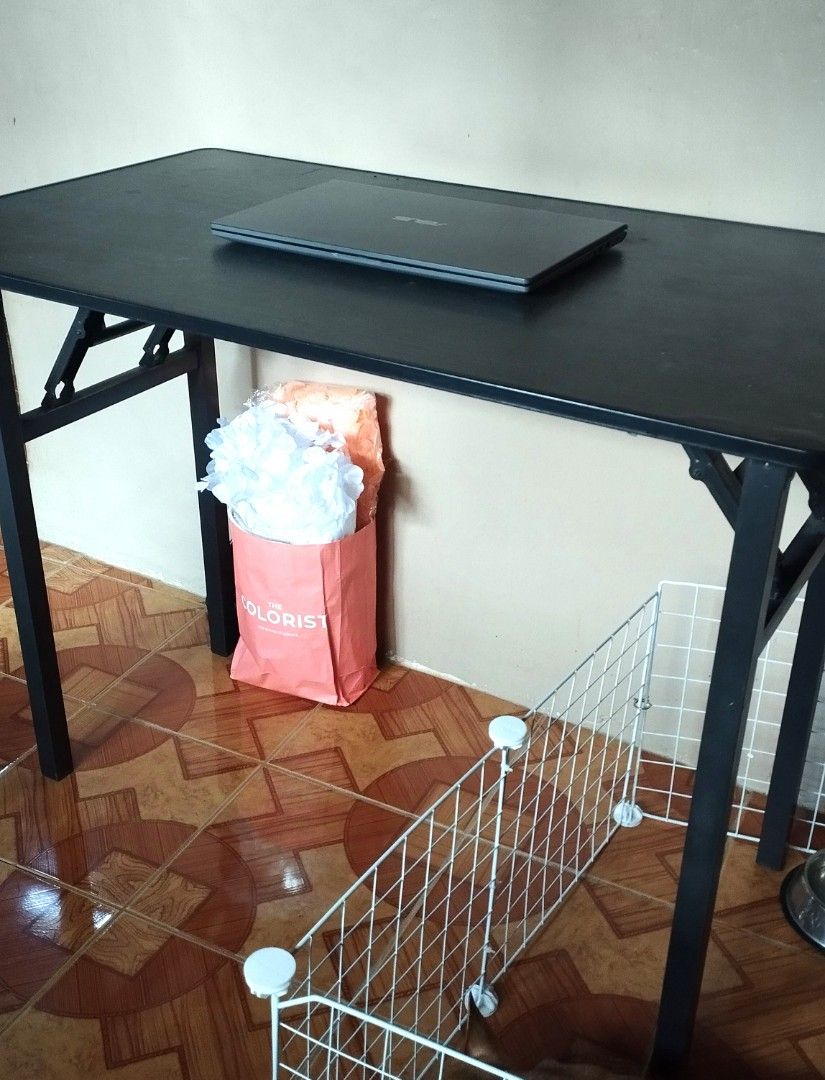Black Foldable Study Table Computer Desk (Category: Tables & Sets) located in Mandaluyong City. Submitted by perfectfashion.mnl (Listing ID 1464817202, Image 3). Description: - Color & Finish: Black frame with a smooth dark wood-grain top - Space-Saving: Folds completely flat for easy storage and moving - Size & Use: Ideal for laptops, studying, and small bedrooms - Stability: Sturdy build with a locking brace (no wobble when set up properly) - C
