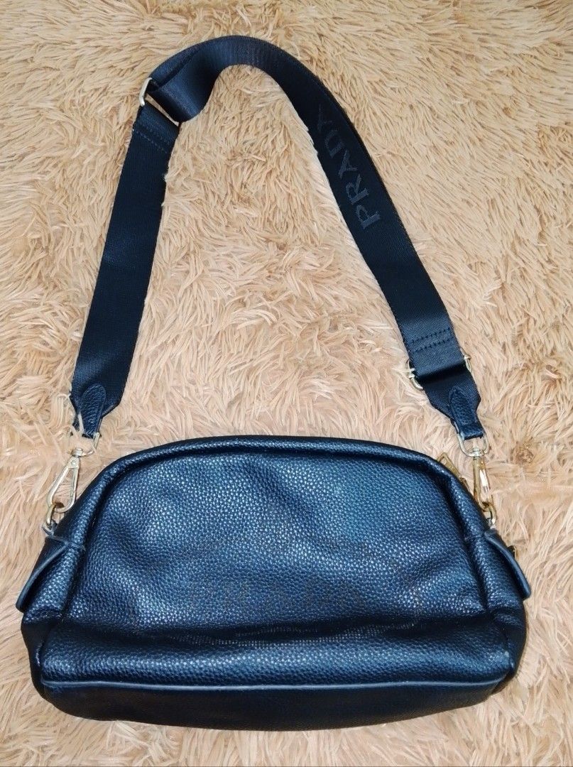 Black leather crossbody bag with Prada strap (Category: Luxury Bags & Wallets) located in Manila. Submitted by crazyjhoyz (Listing ID 1464775068, Image 2). Description: Preloved Bags Take all 350 pesos❣️ Black textured leather handbag with a dome shape. Solid black body, soft pebble texture finish. Wide black fabric strap includes the Prada brand name spelled out in capital letters. Gold tone hardware on the strap clasps. Zipper closure along the