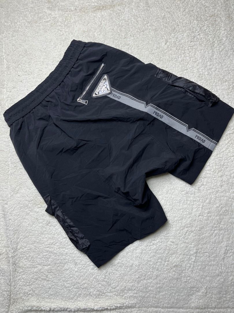 Black Nylon Cargo Shorts with Drawstring and Branding (Category: Shorts) located in Leyte. Submitted by carlthriftwearapparel (Listing ID 1464821122, Image 1). Description: - Color: Black - Material: Lightweight nylon, clean and ready to wear - Fit: Regular fit with elastic waistband and adjustable drawstring - Pockets: Multiple utility pockets with shiny dark fabric flaps plus a back zipped pocket - Details: Branded logo patch and striped tape w