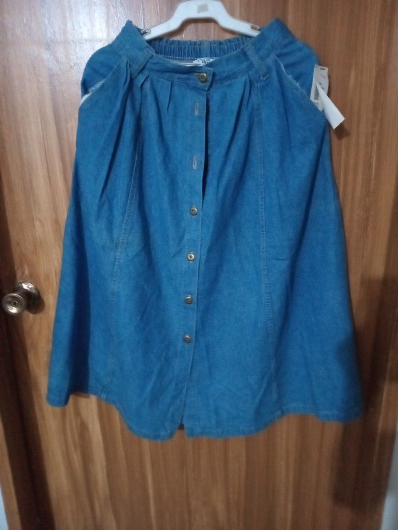Blue denim midi skirt with front button closure (Category: Skirts) located in Marikina City. Submitted by joyful.finds (Listing ID 1464781132, Image 1). Description: - Brand new with tags still attached - Medium wash blue denim midi skirt - Front button-down closure with stylish metal buttons - Chic pleated front design - Comfortable elastic waistband at the back - Comes with two functional side pockets - Versatile piece for any casual outfit.