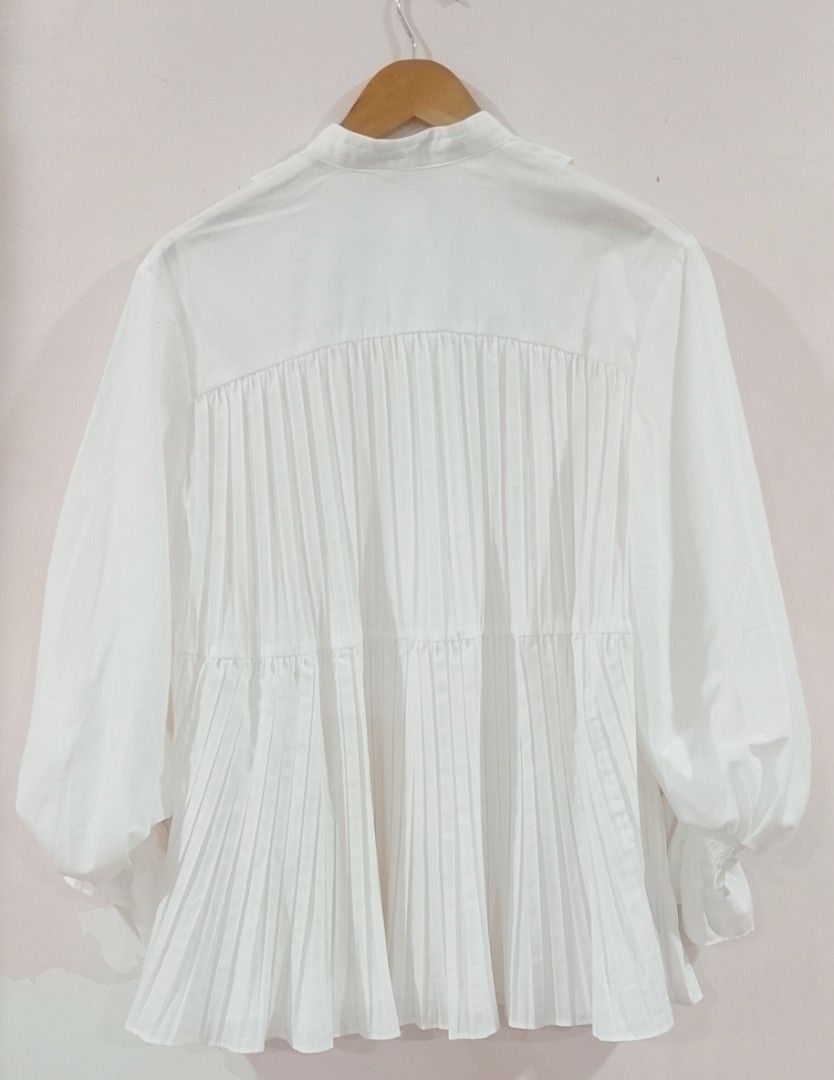 BNWT SNIDEL white Pintuck Frill Tunic Blouse (Category: Blouses) located in Cabanatuan. Submitted by miss.maia (Listing ID 1464847608, Image 2). Description: SNIDEL Pintuck Frill Tunic Blouse This romantic, vintage-inspired white top features a banded high-neck collar, a pleated bib-front panel with stitched accents, and dramatic, voluminous balloon sleeves that taper down into tiered ruffle cuffs. The lower half of the shirt is styled with verti