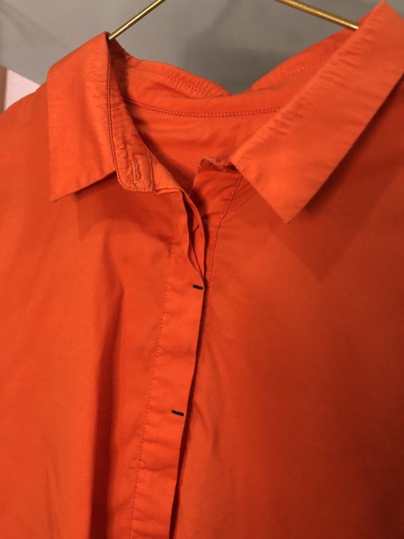 Bright Orange Button-Down Shirt with Front Pockets (Category: Shirts) located in Cauayan City . Submitted by wholly.craaaft (Listing ID 1464946478, Image 2). Description: - Color: Vibrant orange - Style: Button-down with classic collar - Sleeves: Long sleeves with button cuffs - Pockets: Two functional front flap pockets - Back Detail: Pleated design with a gathered hem - Material: Lightweight and versatile for any occasion.
