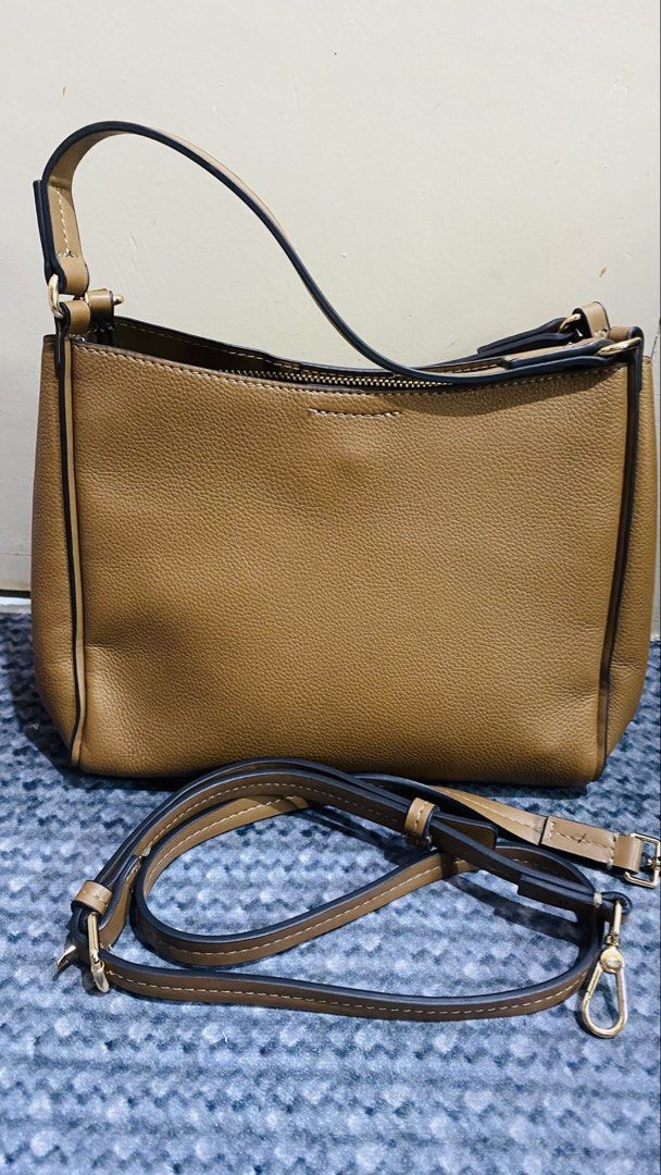 Brown Faux Leather Shoulder Bag with Adjustable Strap (Category: Cross-body Bags) located in Santiago. Submitted by kjuvieann39 (Listing ID 1464803952, Image 1). Description: - Color/Material: Brown pebbled faux leather - Hardware: Gold-tone throughout - Compartments: Center zippered divider with two open sections - Interior: Black fabric lining with an inner zip pocket and branded leather patch - Strap: Includes matching adjustable and detachabl