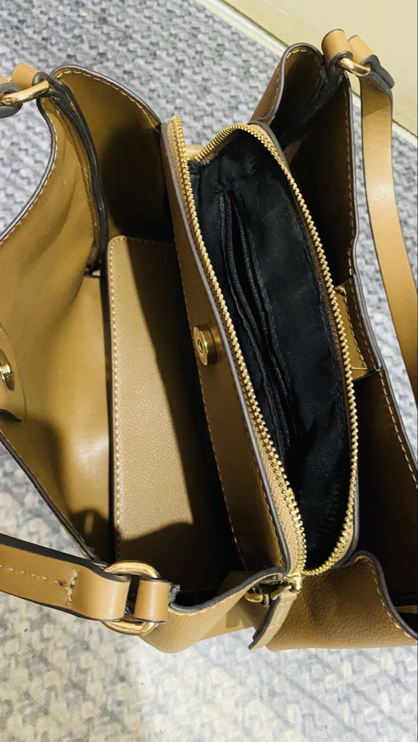Brown Faux Leather Shoulder Bag with Adjustable Strap (Category: Cross-body Bags) located in Santiago. Submitted by kjuvieann39 (Listing ID 1464803952, Image 3). Description: - Color/Material: Brown pebbled faux leather - Hardware: Gold-tone throughout - Compartments: Center zippered divider with two open sections - Interior: Black fabric lining with an inner zip pocket and branded leather patch - Strap: Includes matching adjustable and detachabl