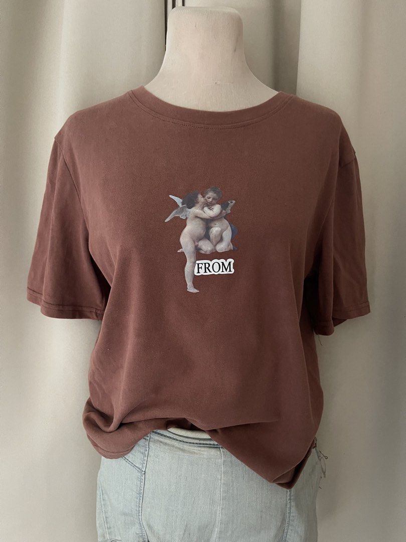 Brown Graphic Tee (Category: Shirts) located in Cainta. Submitted by zlove111 (Listing ID 1464807290, Image 2). Description: - Color: Brown - Design: Renaissance-style angel graphic with 'FROM' text on the chest - Fit: Relaxed fit with a classic crew neck - Material: Soft, cotton knit - Style: Versatile staple for casual everyday outfits large .