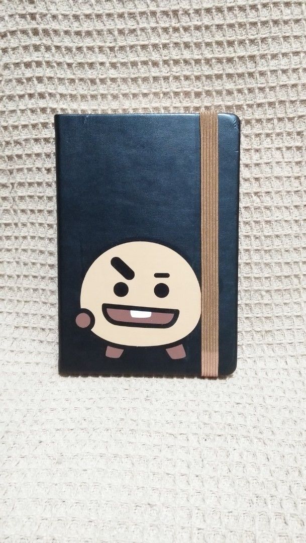 BT21 Shooky Notebook Official BT21 Merchandise (Category: Stationery & School Supplies) located in Valenzuela. Submitted by graciadianna (Listing ID 1464870463, Image 1). Description: - Item: BT21 Shooky Notebook - Material: Black leatherette cover with brown elastic closure band - Details: Official BT21 copyright stamp on the back - Pages: Lined paper with cute character border designs - Condition: Brand new and unused - Ideal for: School, journ